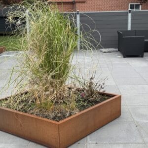 Græs i rusten plantekasse på terrasse