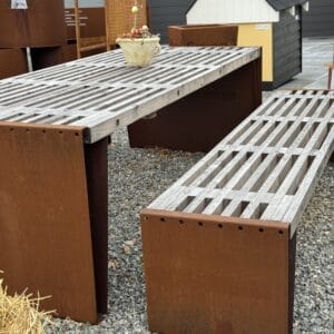 Rustik udendørs metalbord og bænk på grus.